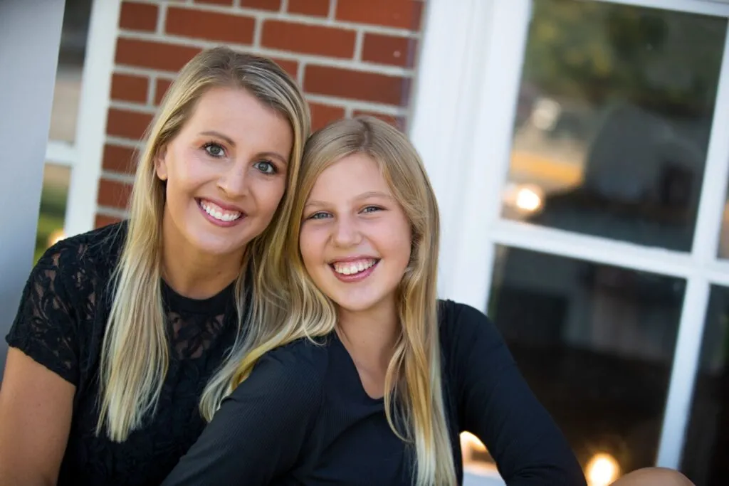Smiling woman and girl sitting together, showcasing healthy smiles, emphasizing the benefits of Invisalign treatment for families in Sioux Falls.