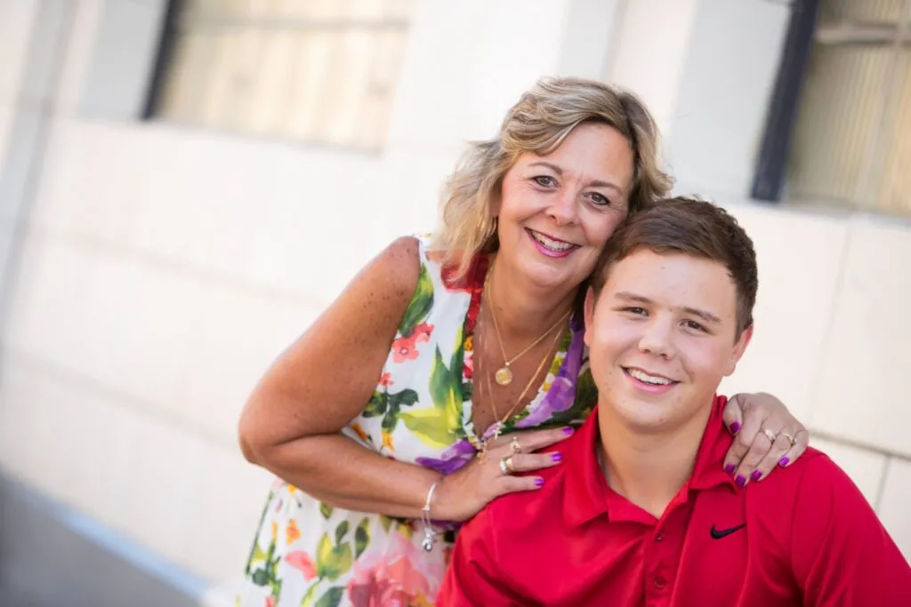 Smiling mother and son posing together outdoors, showcasing a supportive family relationship, relevant to adult orthodontic care and self-esteem.
